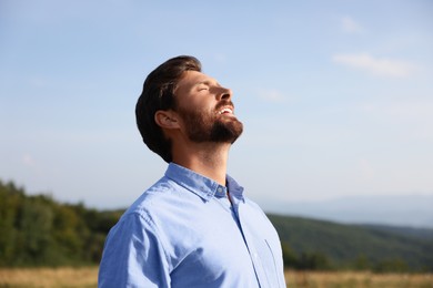 Photo of Happy man enjoying feeling of freedom against sky outdoors