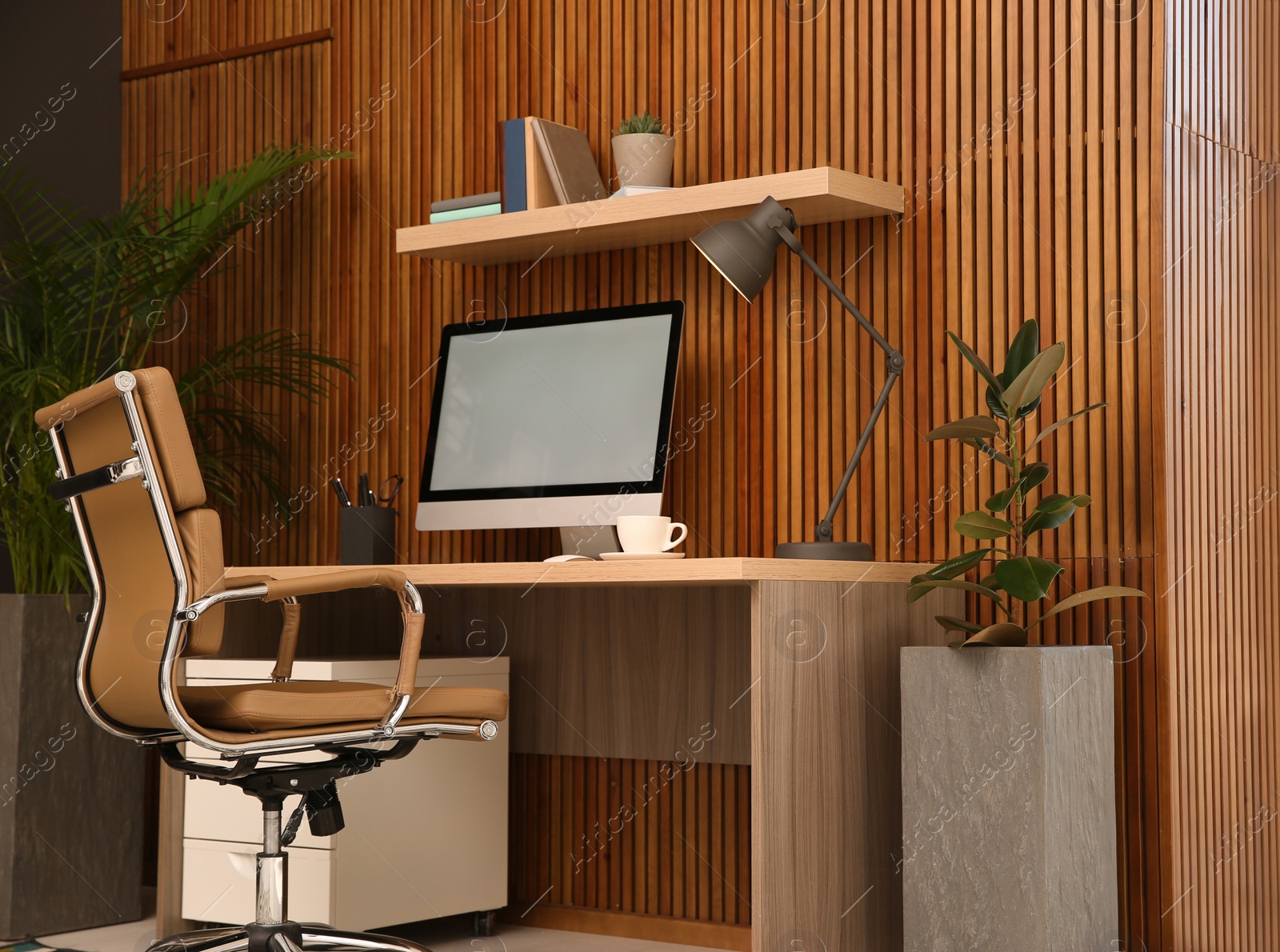 Photo of Comfortable workplace with computer near wooden wall in stylish room interior. Home office design