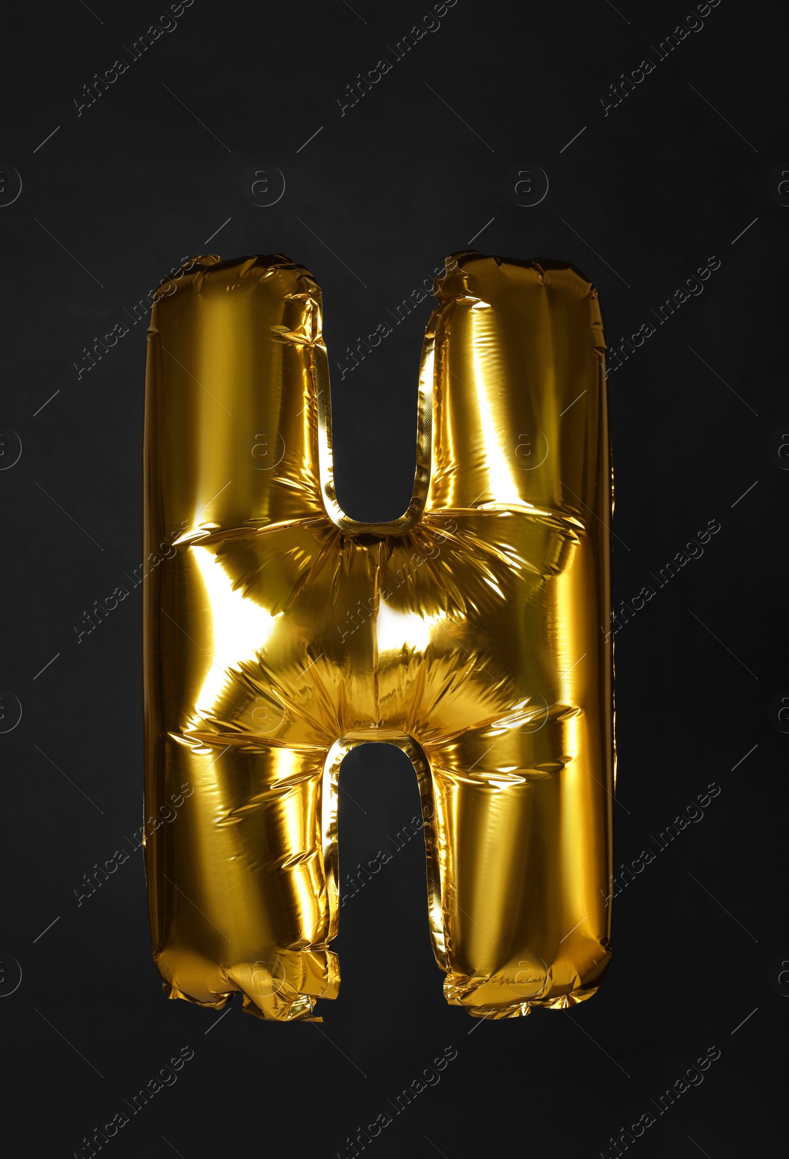 Photo of Golden letter H balloon on black background