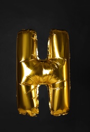 Photo of Golden letter H balloon on black background