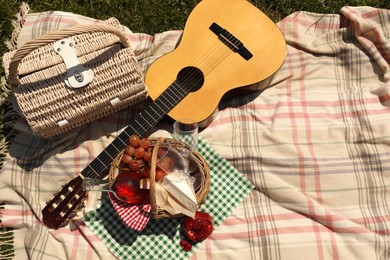 Photo of Picnic basket with delicious food and guitar on blanket, flat lay. Space for text