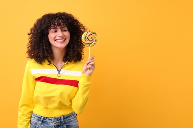 Photo of Beautiful woman with lollipop on yellow background, space for text