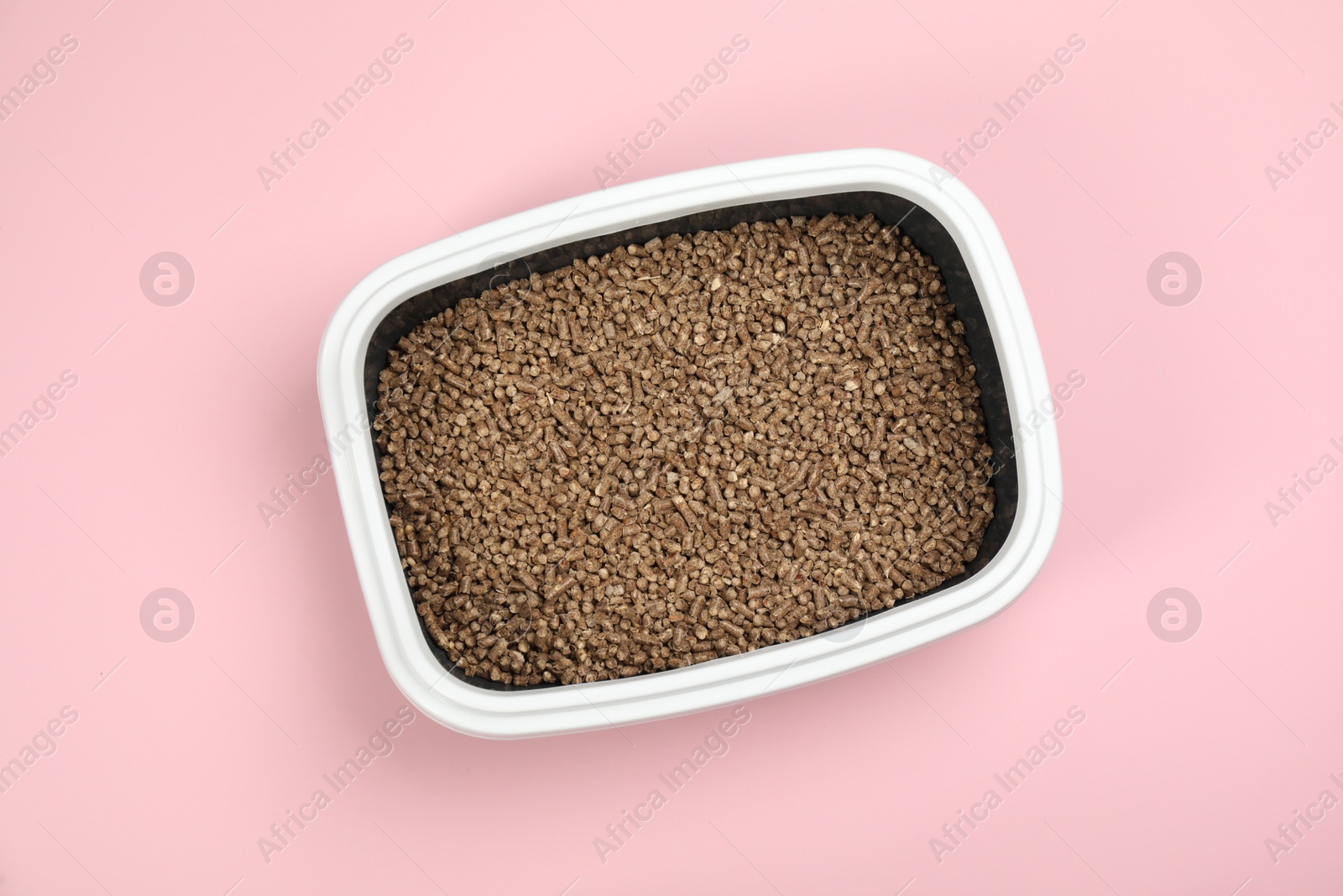 Photo of Cat litter tray with filler on pink background, top view