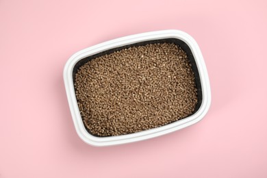 Photo of Cat litter tray with filler on pink background, top view