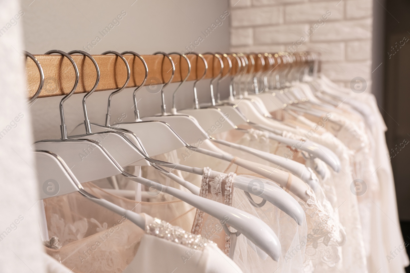 Photo of Different wedding dresses on hangers in boutique, closeup