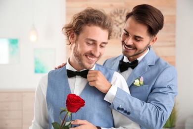Happy newlywed gay couple with flower at home