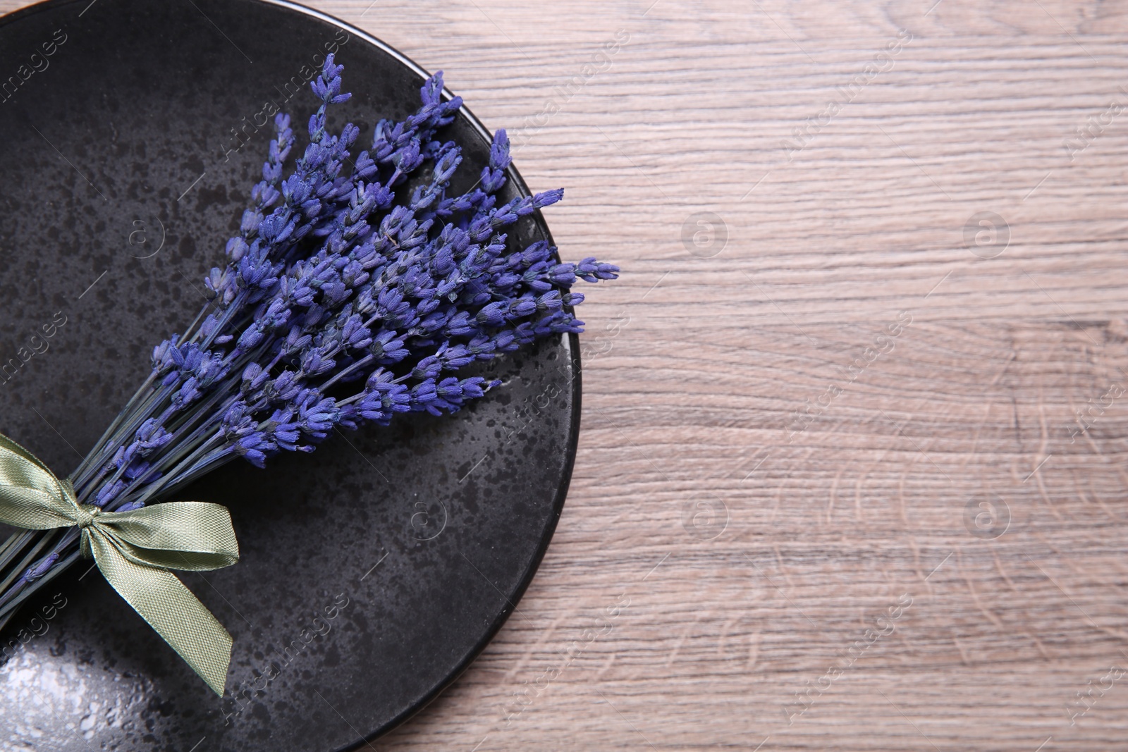 Photo of Bouquet of beautiful preserved lavender flowers and plate on wooden table, top view. Space for text