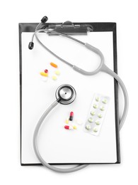 Stethoscope, pills and clipboard isolated on white, top view. Medical tool