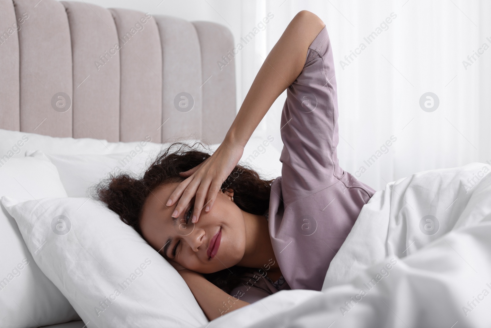 Photo of Happy African American woman awakening in bed at home