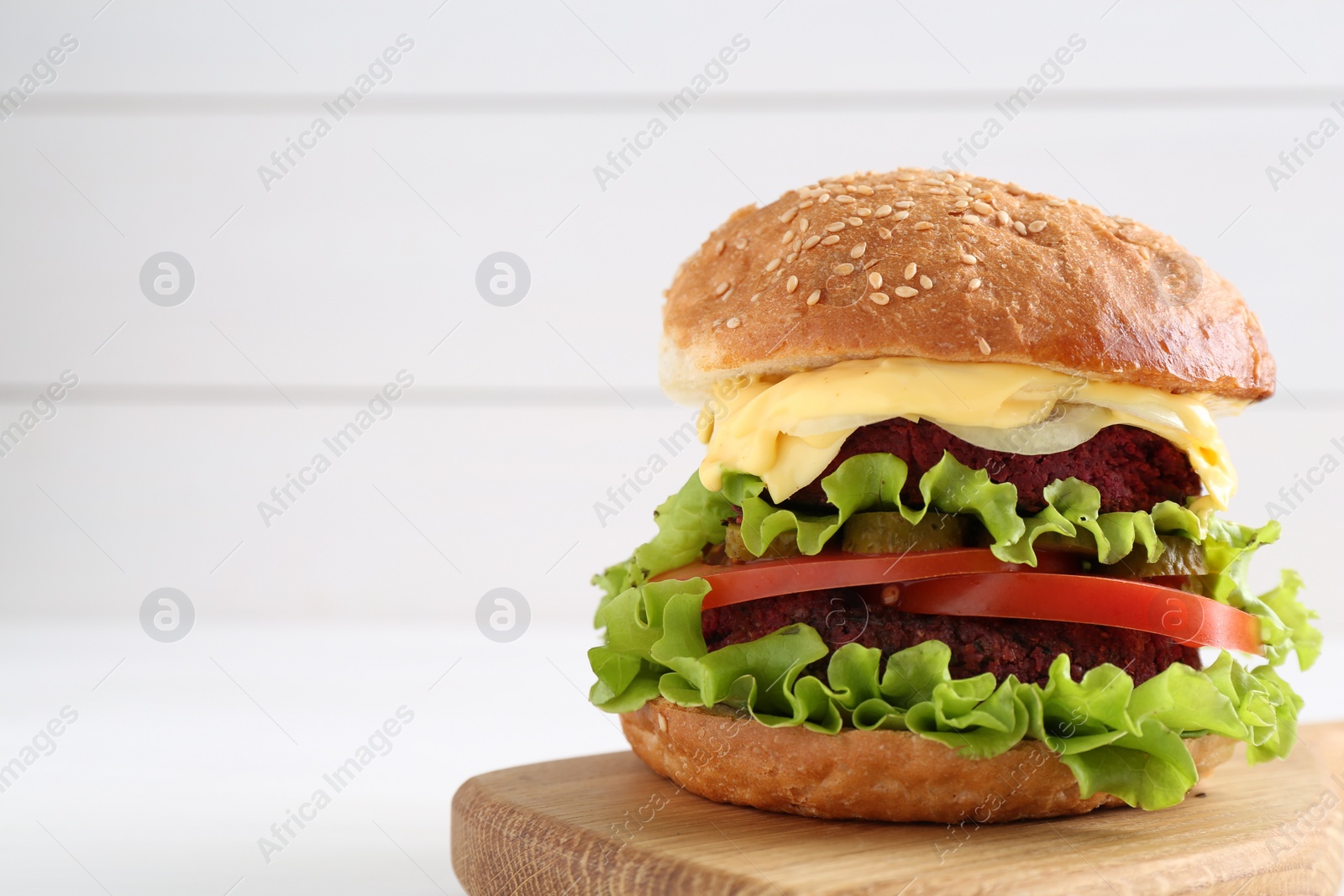 Photo of Delicious vegetarian burger on white table, space for text