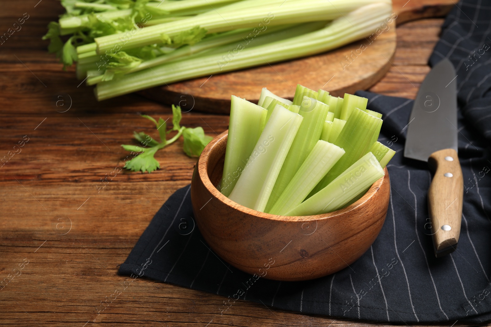 Photo of Fresh green celery and knife on wooden table