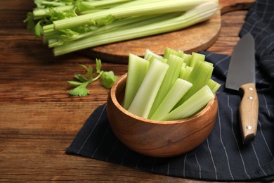 Photo of Fresh green celery and knife on wooden table