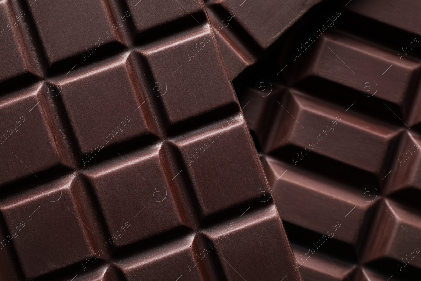 Photo of Many delicious dark chocolate bars as background, top view