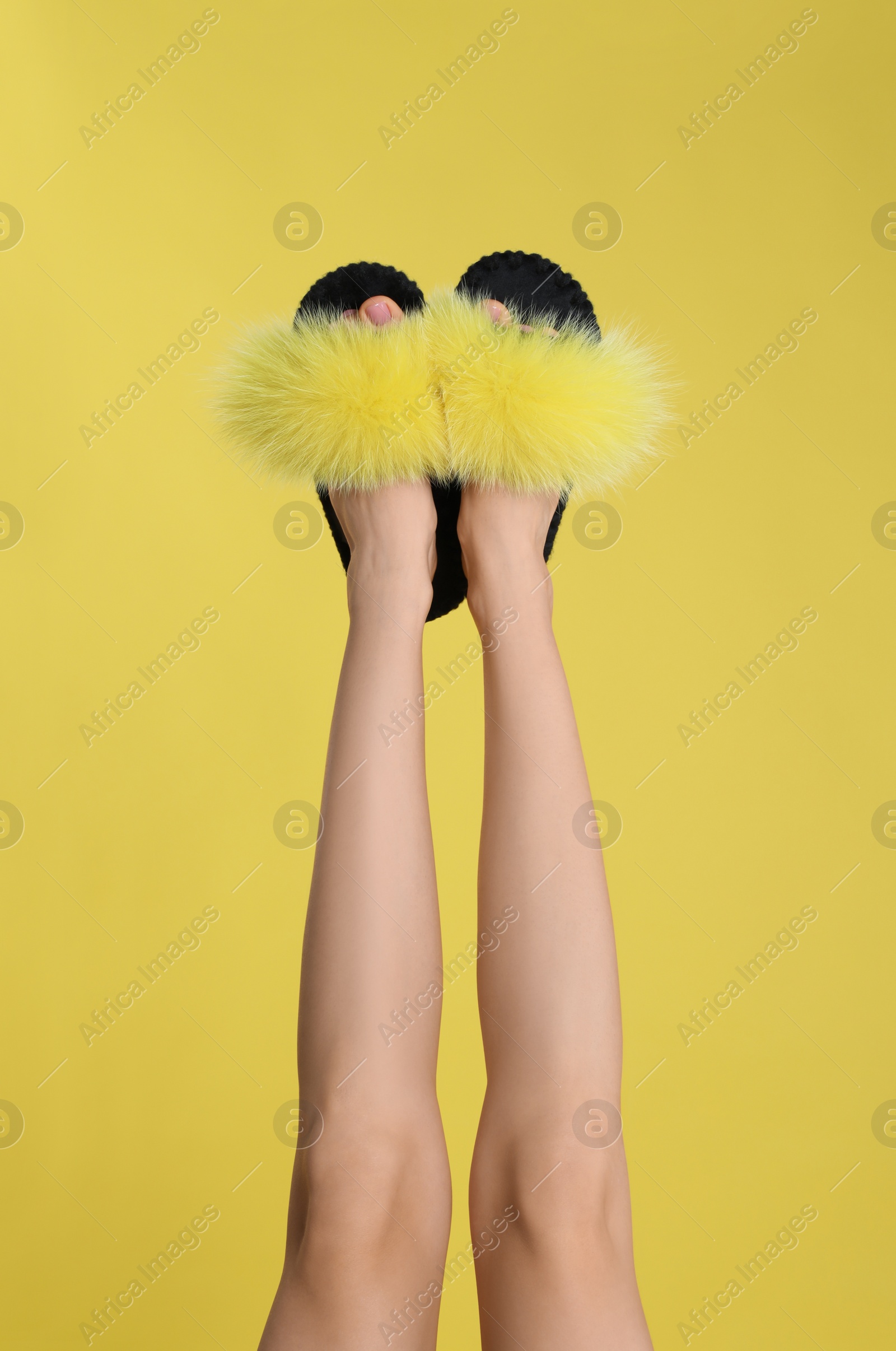 Photo of Woman wearing stylish slippers on yellow background, closeup