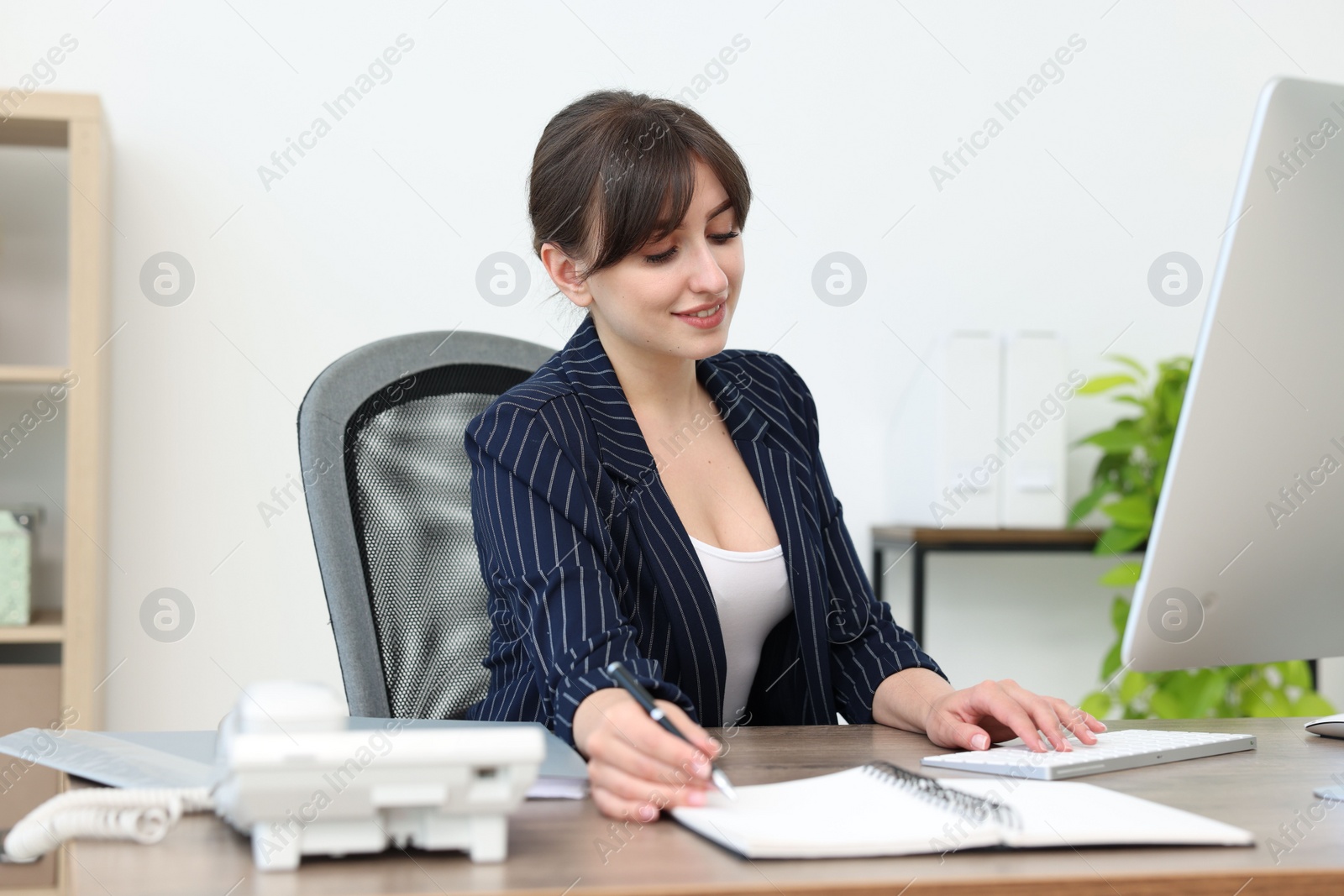 Photo of Smiling secretary working at table in office