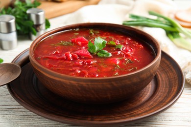 Photo of Stylish brown clay bowl with Ukrainian borsch served on white wooden table