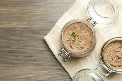 Photo of Glass jars with delicious liver pate on wooden table, top view. Space for text