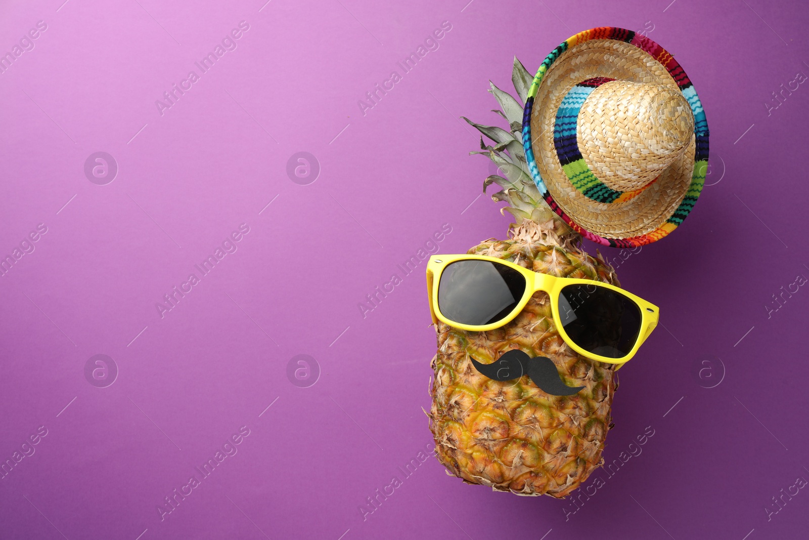 Photo of Pineapple with Mexican sombrero hat, fake mustache and sunglasses on purple background, flat lay. Space for text