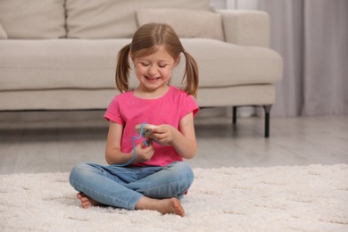 Photo of Cute little girl playing with wooden lacing toy indoors