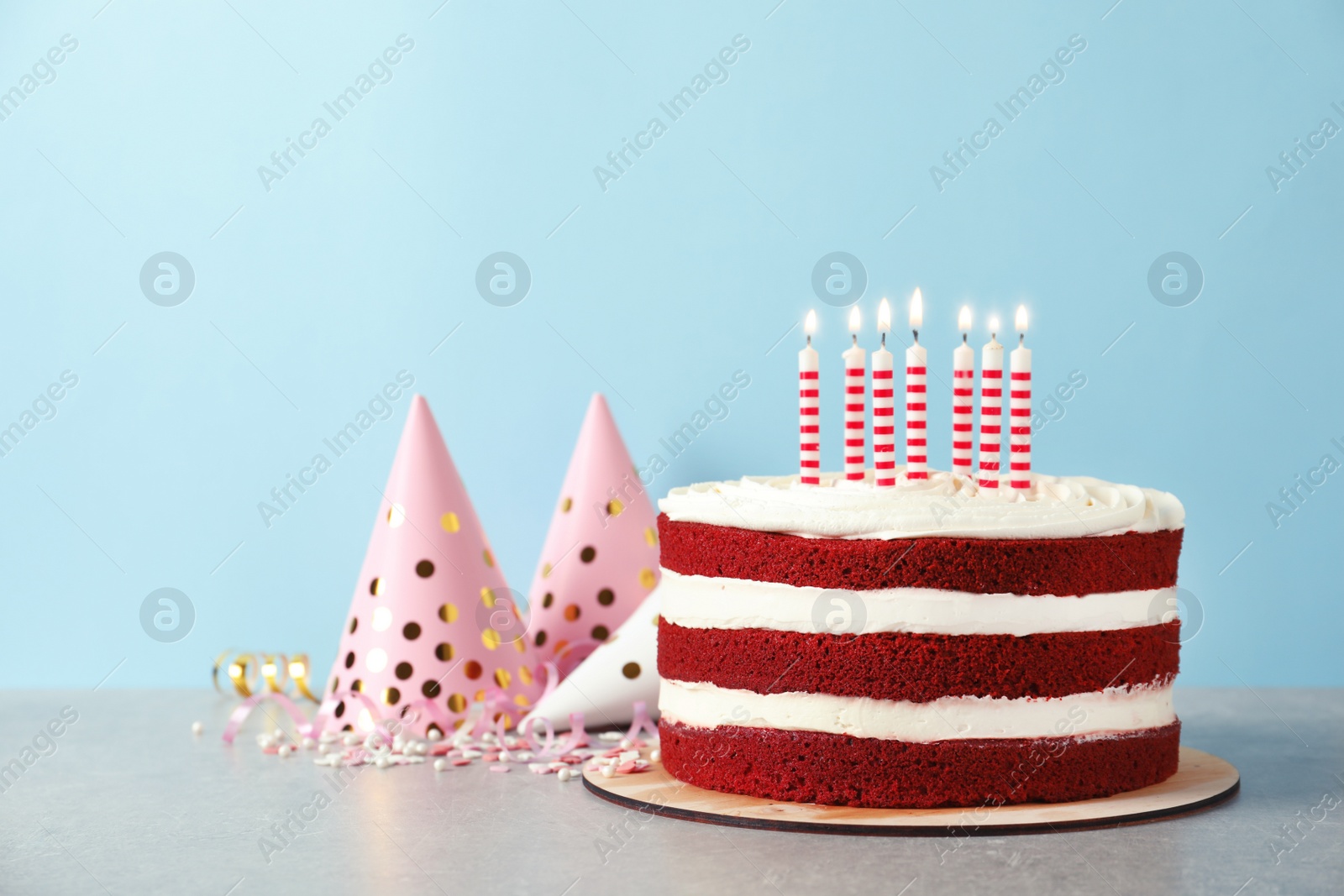 Photo of Delicious homemade red velvet cake with candles on table against color background. Space for text