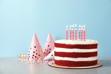 Photo of Delicious homemade red velvet cake with candles on table against color background. Space for text