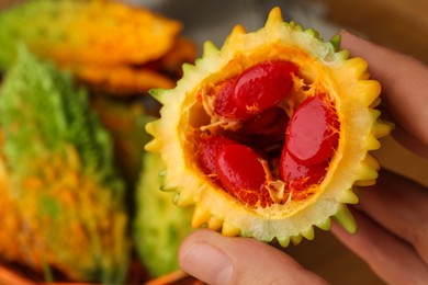 Photo of Woman showing half of fresh bitter melon, closeup