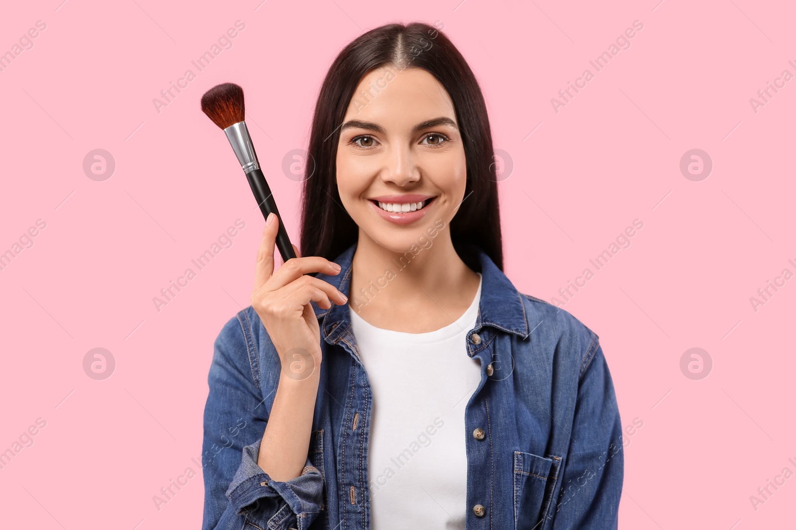 Photo of Beautiful woman with makeup brush on pink background