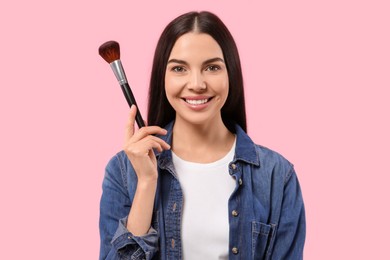 Photo of Beautiful woman with makeup brush on pink background