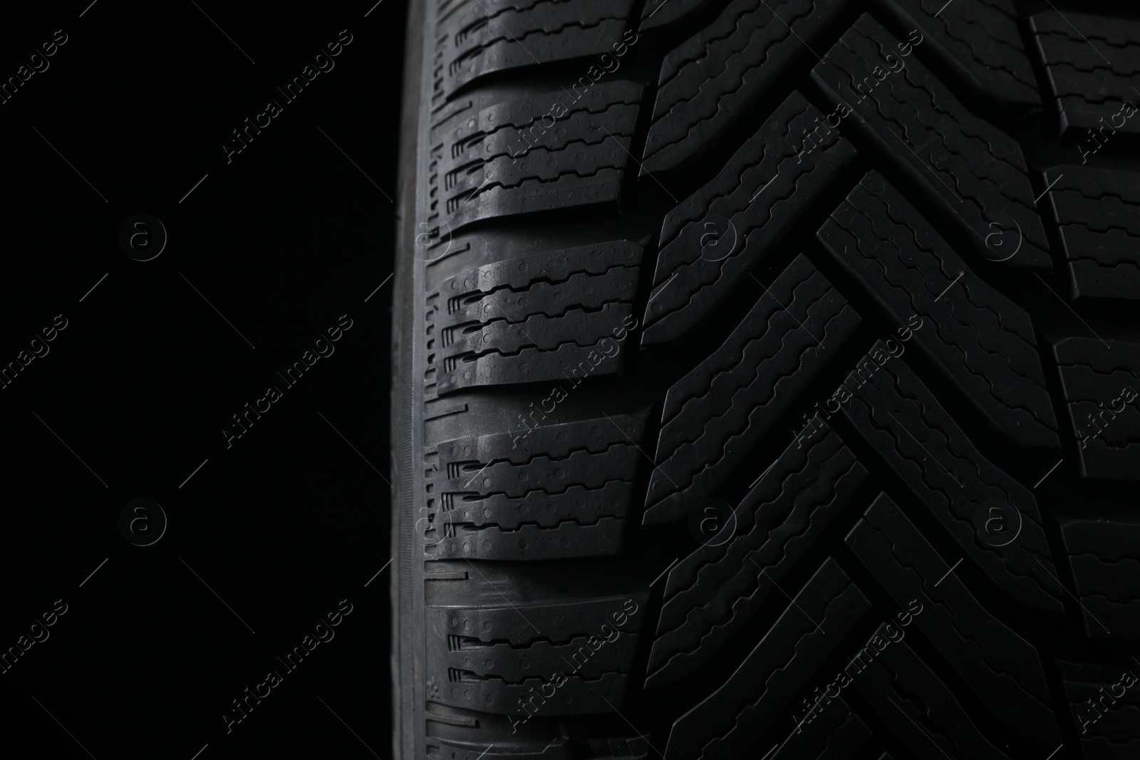 Photo of Winter tire on black background, closeup. Car maintenance
