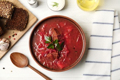 Photo of Stylish brown clay bowl with Ukrainian borsch served on white wooden table, flat lay