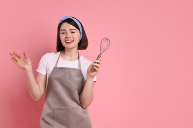 Photo of Happy confectioner with whisk on pink background, space for text
