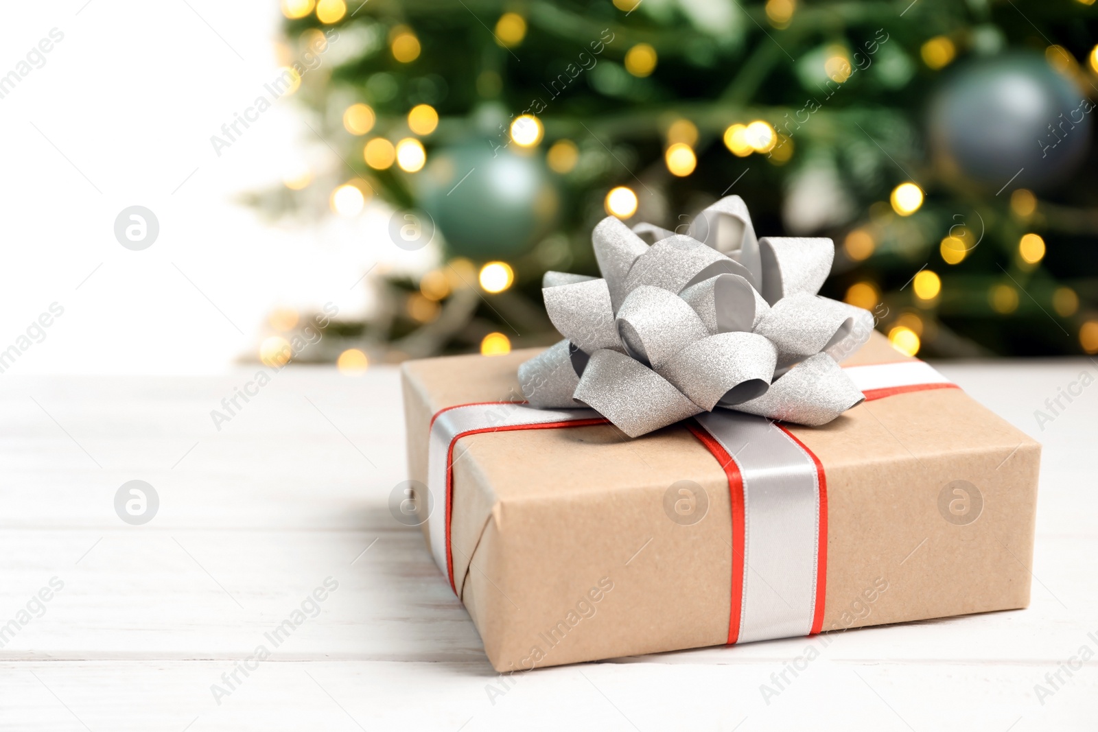 Photo of Beautiful gift box and blurred Christmas tree on background