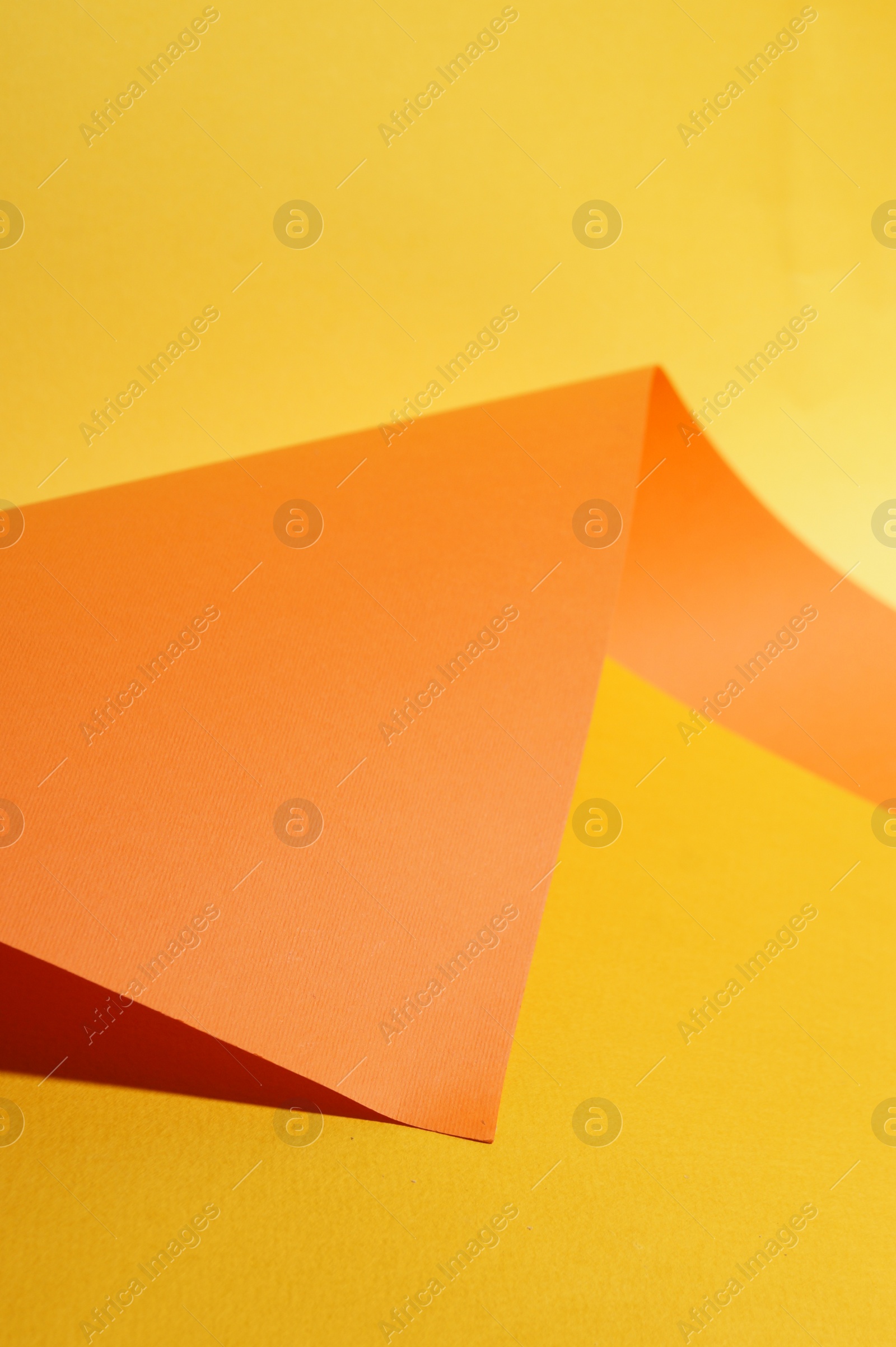 Photo of Bright orange paper sheet on yellow background