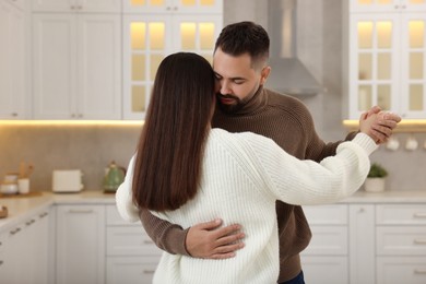 Photo of Affectionate young couple dancing in light kitchen