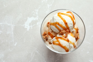 Photo of Bowl with caramel ice cream on light background, top view