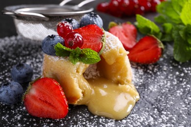 Photo of Tasty vanilla fondant with white chocolate and berries on black table, closeup