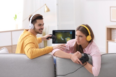 Photo of Emotional young couple playing video games at home