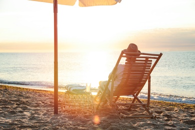 Photo of Man relaxing on deck chair at sandy beach. Summer vacation