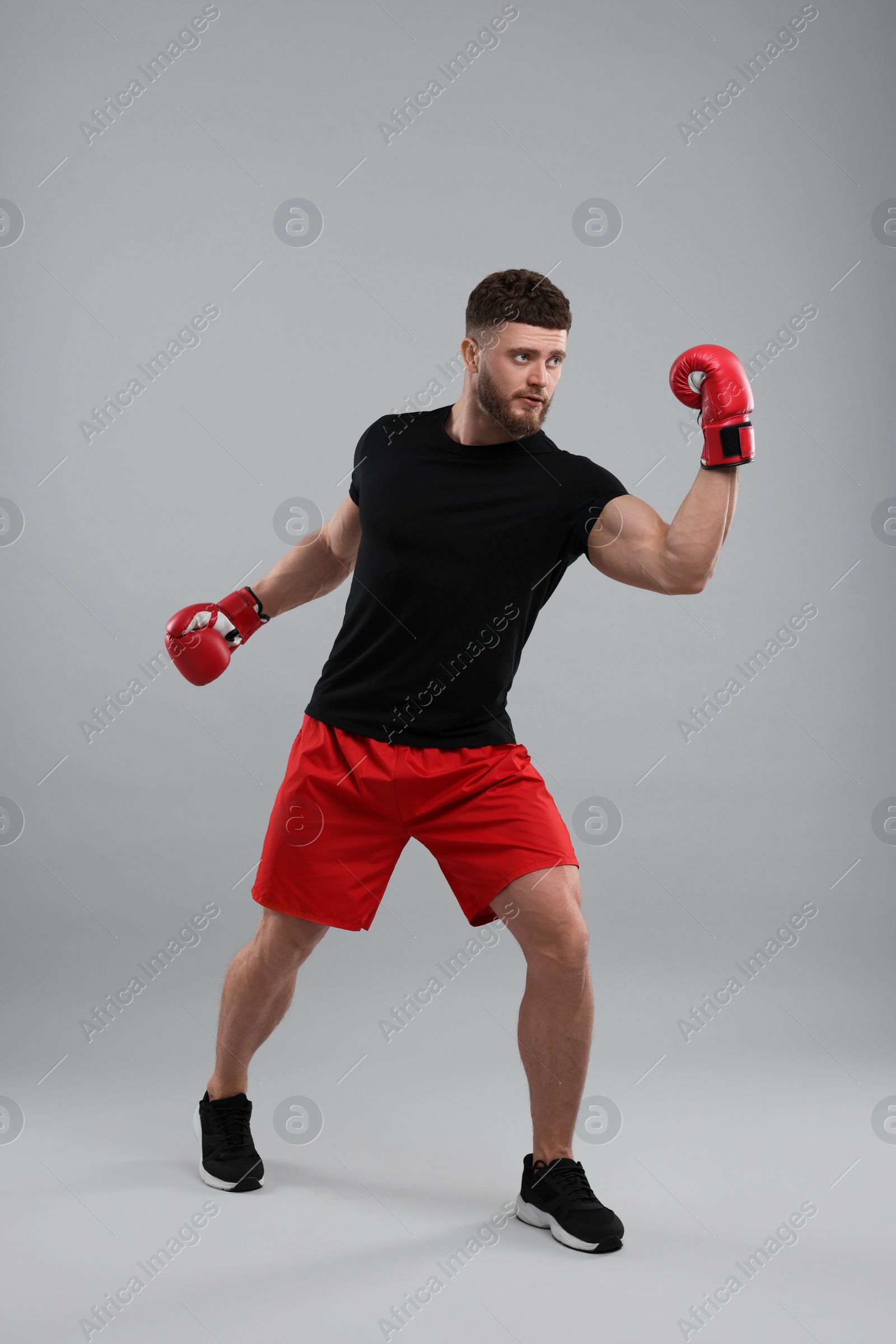 Photo of Man in boxing gloves fighting on grey background