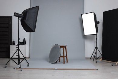 Photo of Stool with light reflector surrounded by professional lighting equipment in photo studio