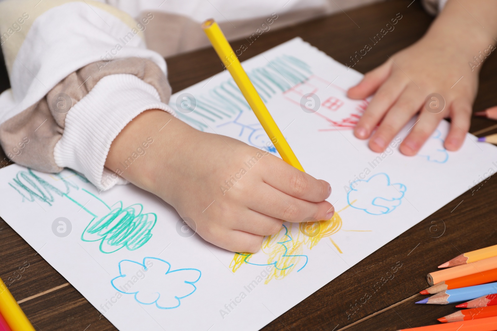 Photo of Little boy drawing with pencil at wooden table, closeup. Child`s art