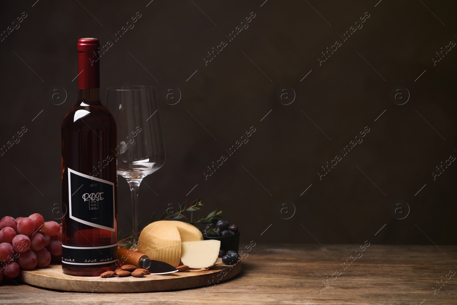 Photo of Bottle of red wine with glass and appetizers on wooden table. Space for text