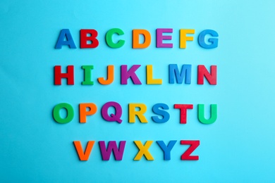 Photo of Colorful magnetic letters on blue background, flat lay. Alphabetical order