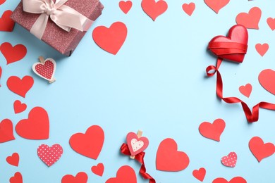 Photo of Flat lay composition with red hearts and gift on light blue background. Space for text