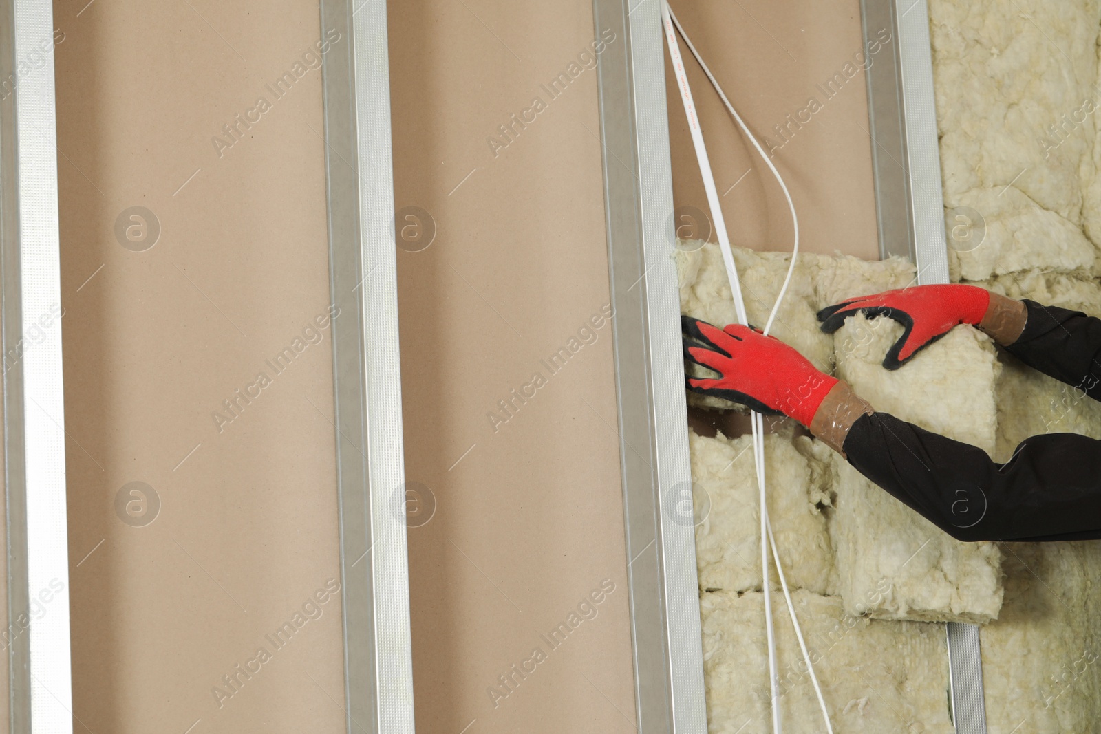 Photo of Worker installing thermal insulation material on wall, closeup