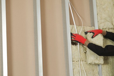 Worker installing thermal insulation material on wall, closeup