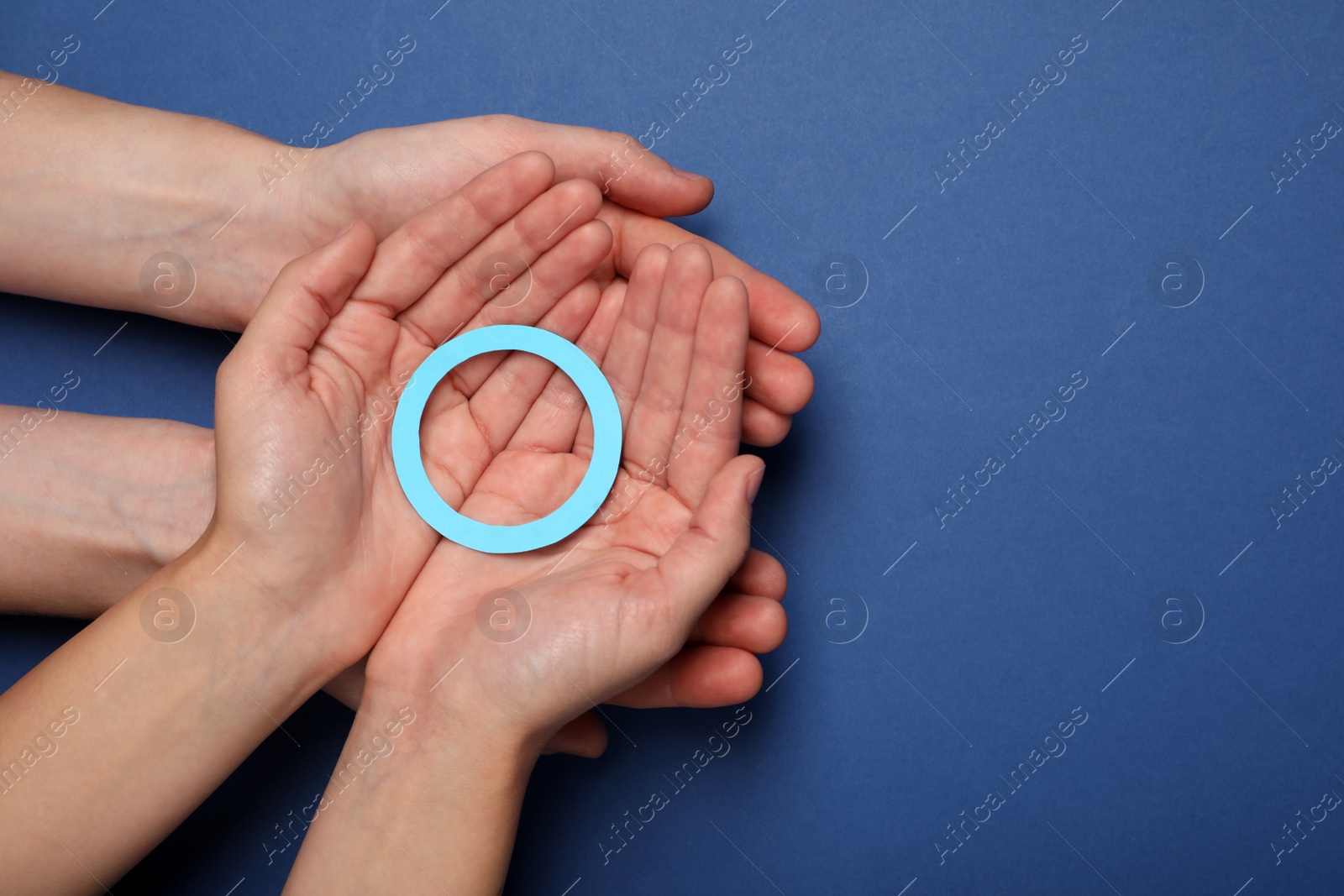 Photo of People showing blue paper circle as World Diabetes Day symbol on color background, top view with space for text