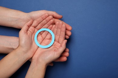 Photo of People showing blue paper circle as World Diabetes Day symbol on color background, top view with space for text