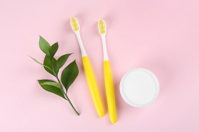 Toothbrushes and bowl of baking soda on pink background, flat lay