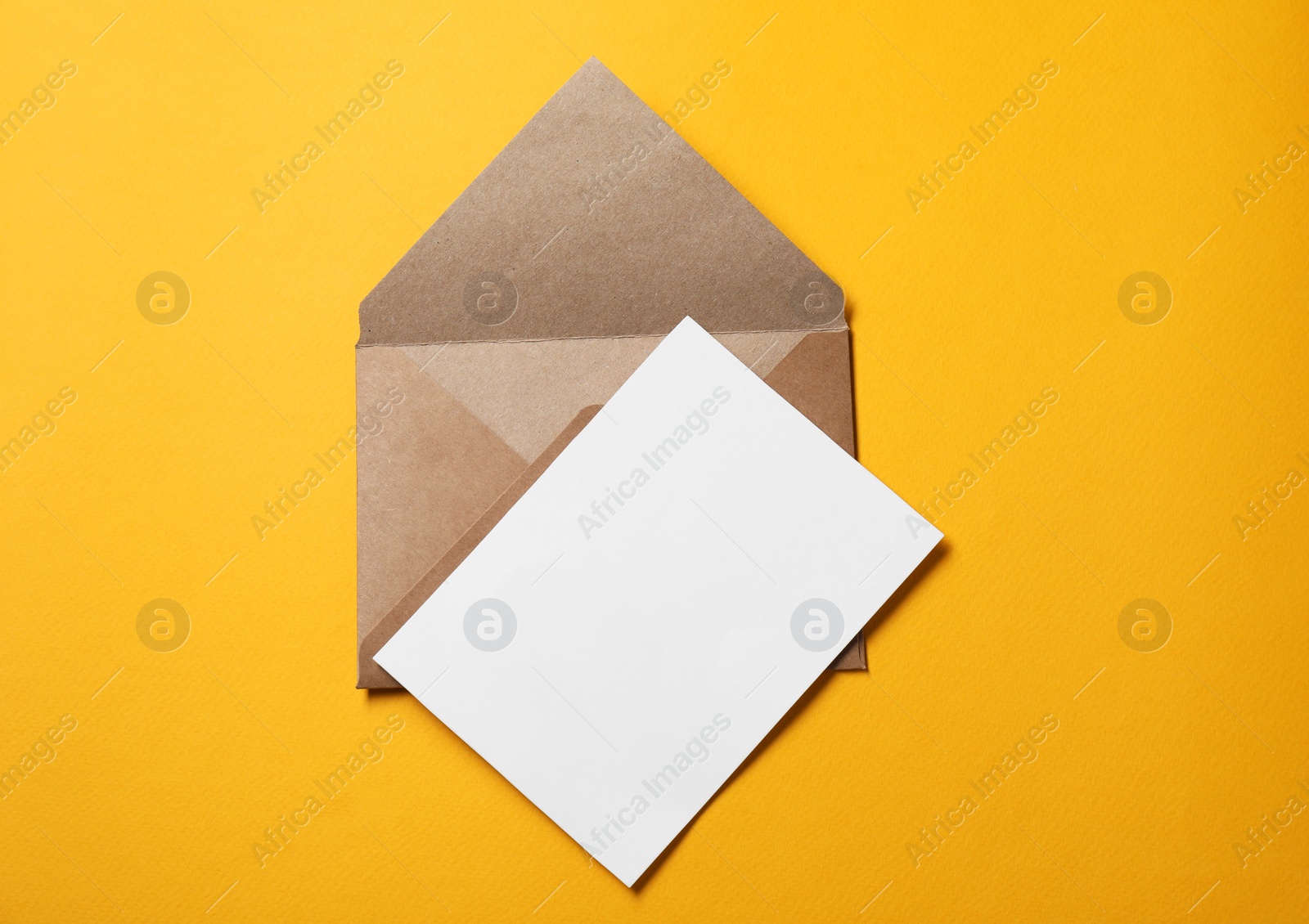 Photo of Blank sheet of paper and letter envelope on orange background, top view